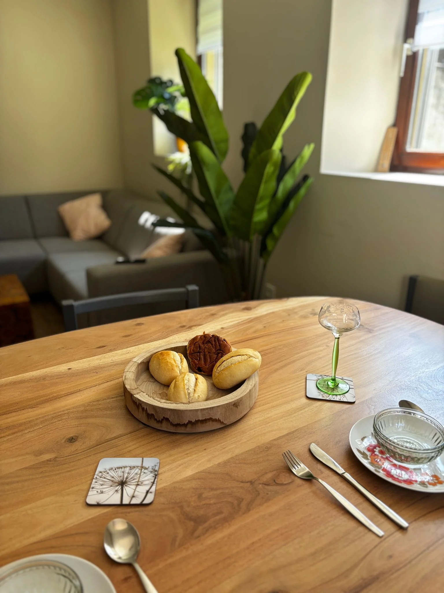 Eettafel met broodje voor een geod ontbijt, daarnaast is er in de foto een gedeelte van de woonkamer (zitbank) te zien. In de foto zijn verder 2 ramen met zicht op het dorp in de eifel duitsland.